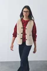 Chaleco de piel sintética negra con textura de borrego, diseño sin mangas y calce relajado. Cuenta con cierre frontal mediante botones y bolsillos laterales.
