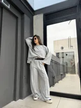 Pantalón de calce holgado color gris, con cintura elástica en contraste color negro, bolsillos laterales y costuras overlock expuestas a lo largo de las piernas.