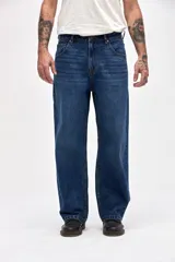 Jean de corte holgado en cadera, cintura y piernas, con diseño clásico de cinco bolsillos y cierre frontal con botón y cremallera.