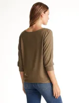 Blusa de tejido acanalado con cuello redondo y mangas tres cuartos. Presenta detalle de tachas metálicas a lo largo de los hombros y mangas, con puños elastizados.