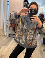 Camisa oversize combinada de denim azul y tela vintage con estampado geométrico multicolor en tonos rojos, naranjas y celestes. Cuenta con cierre frontal de botones, cuello camisero y mangas largas.