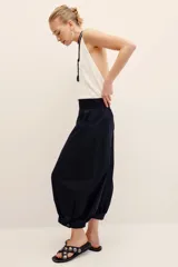 Pantalón negro de algodón con diseño tipo bombacho, cintura elástica ancha y bolsillos laterales. Presenta detalles de ojales metálicos en los dobladillos de las botamangas.