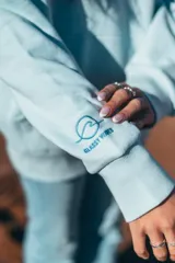 Hoodie celeste con capucha, puños y ruedo acanalados. Presenta un bordado en el pecho con motivos playeros y la frase "Glassy Waves".