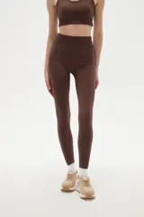 Calza deportiva de tiro alto y ajuste ceñido al cuerpo, confeccionada en tejido elástico de color bordó.