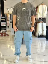 Remera oversize de color celeste con efecto gastado acid wash, mangas cortas y cuello redondo. Cuenta con un gran estampado circular en la espalda con la frase "Not all those who wander are lost" y texto adicional debajo.