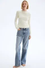 Jeans de cinco bolsillos en denim de algodón con leve stretch, tiro alto y cierre de botón. Corte ajustado de cintura a muslo, y pierna ancha (bootcut) desde la rodilla hasta el bajo. Presenta un lavado celeste medio con efecto desgastado.