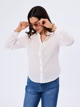 Camisa blanca de algodón con delicado diseño bordado en toda la prenda, cuello clásico, manga larga y cierre frontal abotonado.