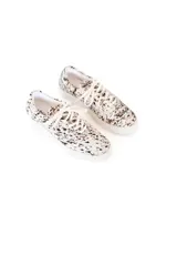 Championes bajos con capellada de pelo de cuero natural con estampado animal print tipo dálmata en tonos blanco y negro, suela plana de goma y cordones al tono.