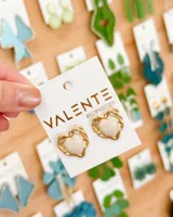 Par de aros tipo botón con forma de corazón, con centro color crema y borde dorado con diseño trenzado.