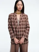 Blazer de corte estructurado con estampado de cuadros en tonos marrones. Presenta solapas clásicas, cierre frontal de un botón y mangas largas.