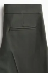 Pantalón sastrero de corte acampanado, con cierre frontal, botón oculto y corchetes. Presenta bolsillos al bies, bolsillos traseros ribeteados y pliegues marcados tanto en la parte delantera como en la trasera.