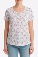 Remera blanca de manga corta con estampado floreado, cuello redondo y detalle de botones frontales.