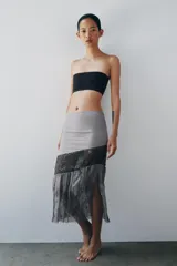Falda midi de tiro medio, color gris, confeccionada en mezcla de lyocell y viscosa, con detalle de apliques de lentejuelas y bajo de tejido transparente plisado con bordados florales.