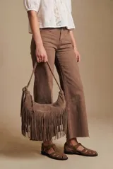 Cartera de hombro con diseño de flecos largos en la parte frontal, confeccionada en material sintético con textura de gamuza. Cuenta con una correa larga ajustable y cierre superior.