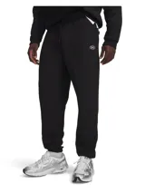 Pantalón de jogging Under Armour modelo Rival Fleece de color negro, con cintura elástica ajustable mediante cordón, bolsillos laterales y puños elásticos en los tobillos. Presenta pequeño logo ovalado bordado en la pierna izquierda.