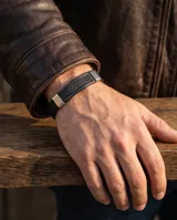 Pulsera de diseño masculino con banda de cuerina negra y placa central de acero con textura geométrica y detalles laterales en acero pulido.