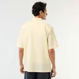 Camisa de manga corta color amarillo, confeccionada en mezcla de lino, con cuello clásico y cierre frontal de botones.