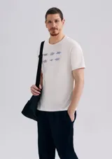 Remera de corte regular color beige con cuello redondo, mangas cortas y estampa frontal de pequeños nudos marineros en tono azul.