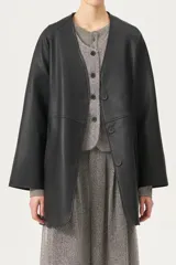 Chaqueta de cuero sintético color negro con diseño estilo kimono y escote en V. Presenta cierre frontal con botones, mangas anchas y un cinturón del mismo material para ajustar la cintura.