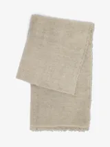 Bufanda fina de tejido ligero y suave, color beige, con bordes deshilachados.