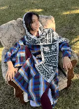 Balaclava tejida con capucha y bufanda integrada, con diseño geométrico y floral en tonos gris y blanco. Presenta detalles de casas y motivos decorativos en el tejido.