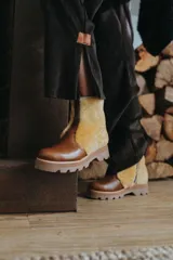 Botas de caña baja combinadas en cuero marrón y corderito en tono mostaza, con suela track gruesa y cierre lateral.