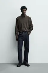 Camisa slim fit de color marrón oscuro, con cuello italiano, manga larga con puños abotonados y cierre frontal de botones. Confeccionada en tejido de fácil cuidado que minimiza la necesidad de planchado.