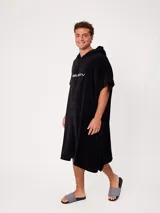 Poncho de toalla negro con capucha y logo bordado en el pecho, diseño amplio y cómodo.