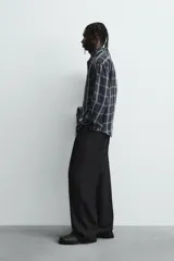 Camisa de corte relajado confeccionada en tejido fluido de cupro y viscosa, con estampado de cuadros, cuello solapa, manga larga con puño abotonado y cierre frontal de botones.