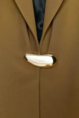 Blazer entallada color tostado con cuello solapa, manga larga y hombreras. Presenta cierre frontal con un botón metálico dorado y bolsillos delanteros de vivo.