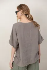 Blusa de lino color blanco, de corte amplio, con escote redondo, mangas cortas y detalle de guarda calada horizontal en la parte inferior.