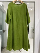 Vestido midi verde de lino, con escote en V, mangas tres cuartos, corte holgado y bolsillos laterales.