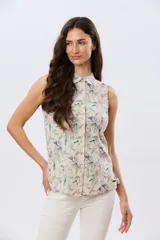 Camisa sin mangas de lino y algodón, con estampado floral en tonos violeta y verde sobre base beige, cuello camisero y cierre frontal de botones.