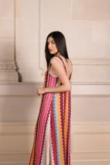 Vestido largo de punto con diseño de rayas verticales en zigzag, escote en V y espalda baja. Presenta detalles de vivos en hilo metalizado lurex.