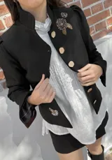 Chaqueta corta azul marino de terciopelo con cuello mao, botones dorados y bordado floral en el frente.