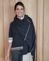 Bufandón de lana lambswool, de textura suave y liviana, con diseño liso y etiqueta de cuero en el extremo inferior.