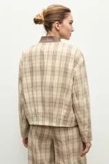 Chaqueta bomber de corte recto con diseño a cuadros, cuello mao en contraste color marrón y cierre frontal de botones a presión oculta.