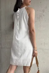 Vestido corto blanco con bordado calado, tirantes finos y corte recto.