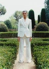 Pantalón de vestir color crema, de corte recto y diseño acampanado, con trabillas en la cintura, bolsillos laterales y cierre oculto.