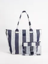 Bolso tipo tote grande a rayas azules y blancas, resistente al agua, con asas largas para el hombro. Incluye un neceser transparente a juego con cierre y detalles a rayas.