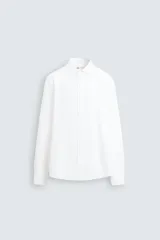 Camisa blanca de corte regular fit, con cuello italiano abierto y manga larga con puño abotonado. Cierre frontal de botonadura.
