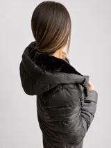 Campera puffer negra con capucha, diseño acolchado, cierre frontal y bolsillos laterales. Presenta un corte entallado y largo a la cadera.
