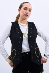 Chaleco negro con apliques de flores y tachas doradas en forma de corazón.
