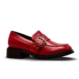 Zapato tipo mocasín de charol negro con taco bajo cuadrado y detalle de tira con hebilla metálica plateada en el empeine.