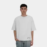 Remera blanca de corte oversize con estampado en tipografía cursiva negra en la espalda.