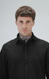 Camisa negra de manga corta con cuello camisero y botones frontales. La tela presenta un patrón texturizado en relieve de motivos florales o abstractos.