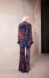Camisa de terciopelo azul con estampado barroco en color naranja, de corte recto, cuello clásico y cierre frontal con botones.