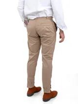 Pantalón de vestir color beige, de corte recto, con bolsillos laterales y traseros. Se ajusta a la cintura con cinturón de cuero marrón.
