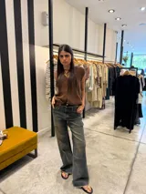 Pantalón de jean de corte ancho y tiro medio, con efecto lavado desgastado en tono azul grisáceo y ruedo desflecado.