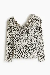 Top entallado de punto con estampado de leopardo, escote asimétrico amplio y un hombro al descubierto. Modelo de manga larga con frunces en el escote para crear un efecto drapeado.